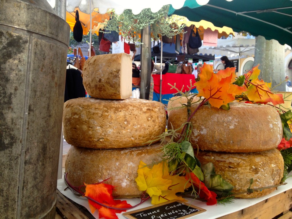 The cheese man decorates his wheels of cheese with autumn leaves